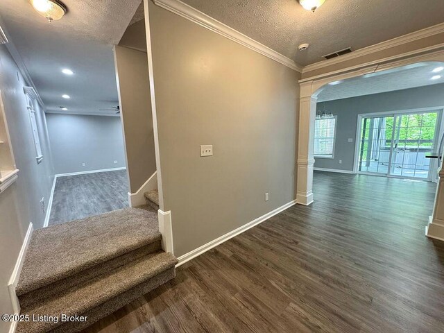 corridor featuring dark wood finished floors, stairway, baseboards, a textured ceiling, and arched walkways
