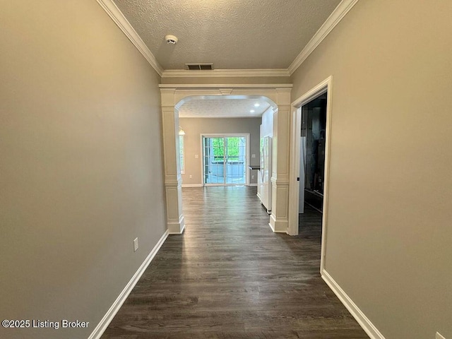 hallway featuring crown molding, dark wood finished floors, visible vents, a textured ceiling, and arched walkways