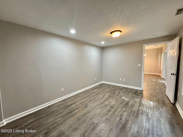 interior space featuring a textured ceiling, baseboards, recessed lighting, and dark wood finished floors