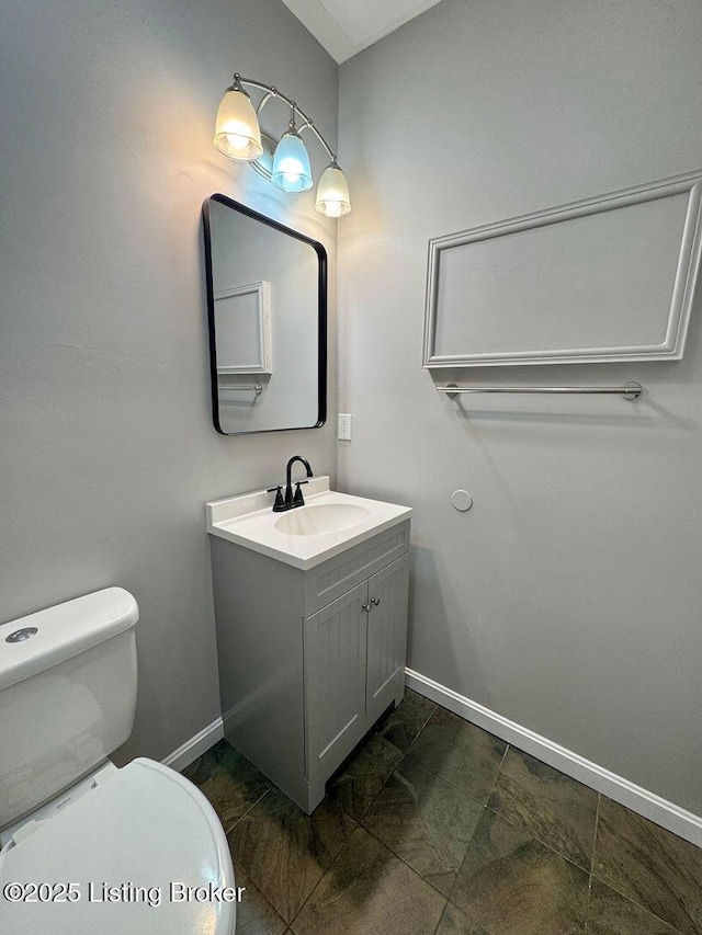 bathroom featuring baseboards, vanity, and toilet