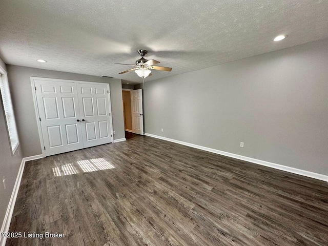 unfurnished bedroom with a closet, a textured ceiling, dark wood-type flooring, baseboards, and recessed lighting