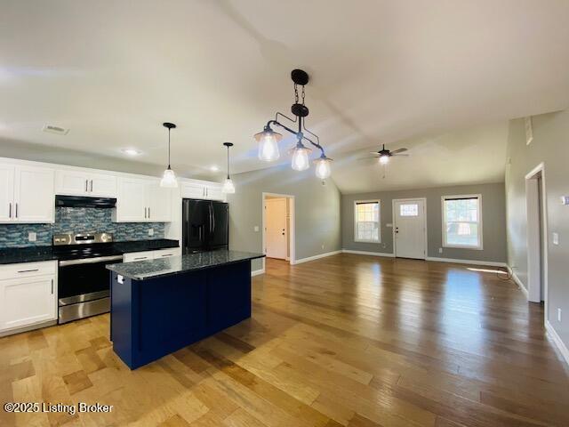 kitchen featuring stainless steel range with electric cooktop, freestanding refrigerator, a ceiling fan, a center island, and under cabinet range hood