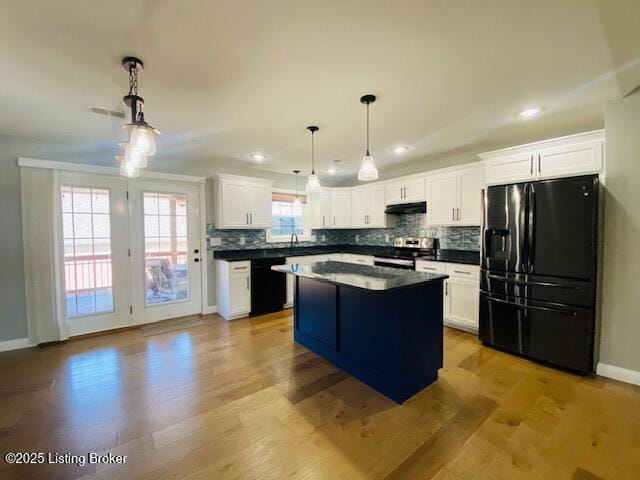 kitchen with under cabinet range hood, tasteful backsplash, light wood-style flooring, and black appliances