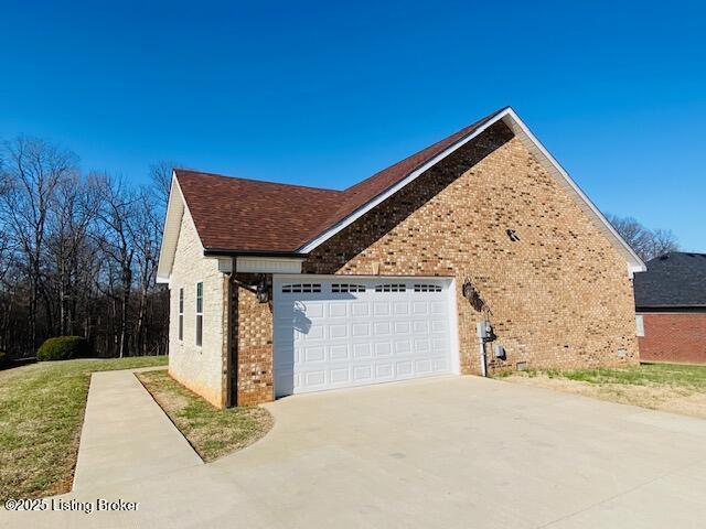 view of side of property featuring a garage, brick siding, and driveway
