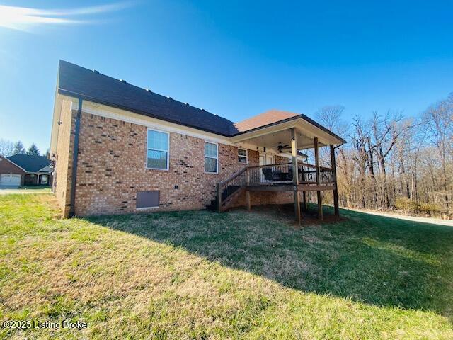 rear view of property featuring brick siding, stairs, a ceiling fan, and a lawn