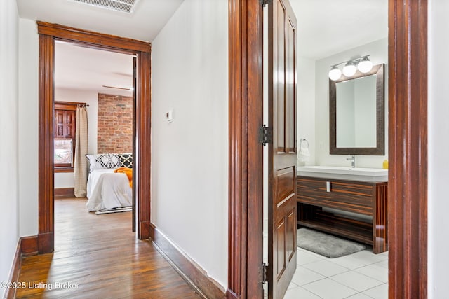 1026 S Brook St, Louisville, KY 40203 - hallway with light wood-style floors, a sink, baseboards, and visible vents