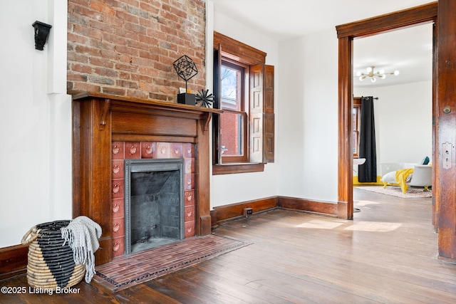 1026 S Brook St, Louisville, KY 40203 - unfurnished living room featuring a tiled fireplace, baseboards, and wood finished floors