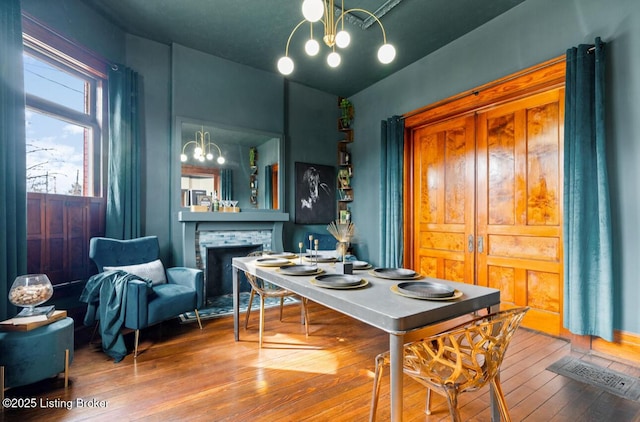 1026 S Brook St, Louisville, KY 40203 - dining area featuring a fireplace, a notable chandelier, visible vents, and wood-type flooring