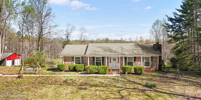 single story home featuring a chimney, a garage, a front lawn, and brick siding