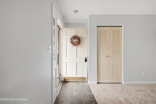 foyer entrance featuring baseboards and stone tile floors