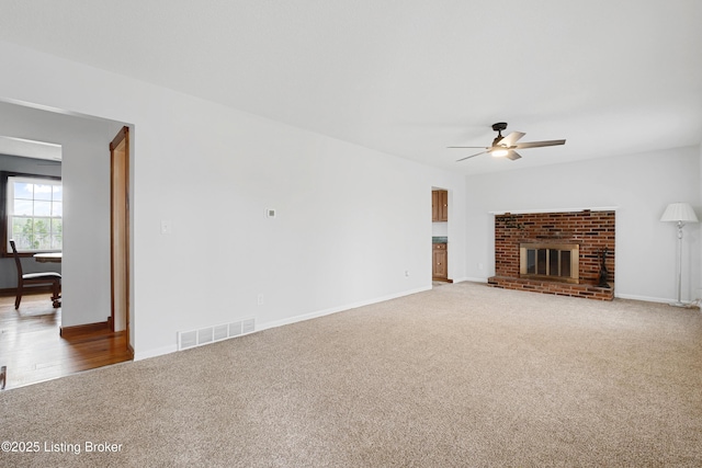 unfurnished living room with visible vents, baseboards, a ceiling fan, a fireplace, and carpet flooring
