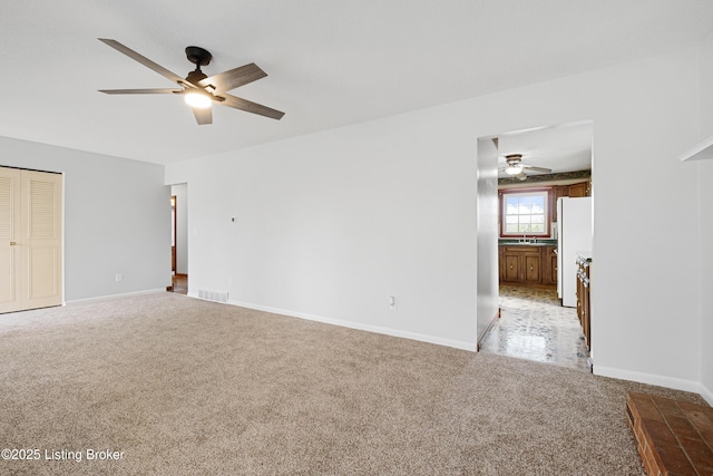 empty room with visible vents, light colored carpet, baseboards, and ceiling fan