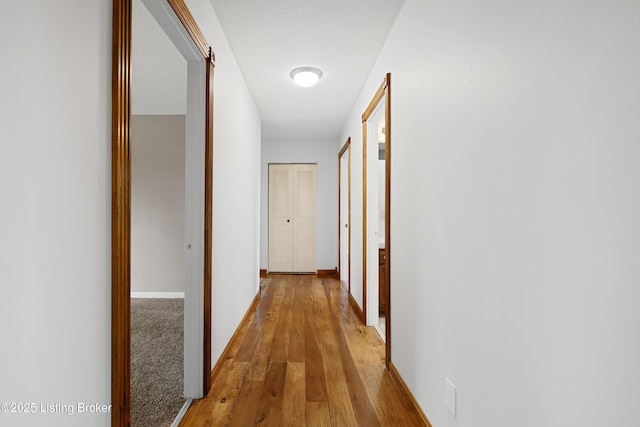 hallway with baseboards and wood finished floors