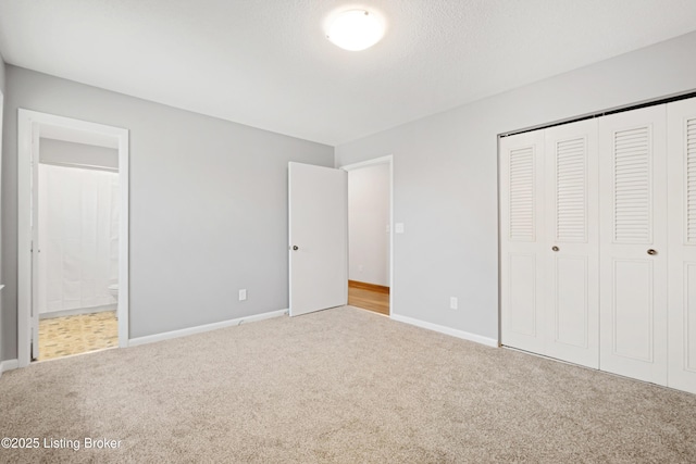 unfurnished bedroom featuring a closet, carpet, baseboards, and connected bathroom