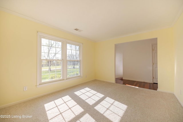 carpeted spare room with baseboards, ornamental molding, and visible vents