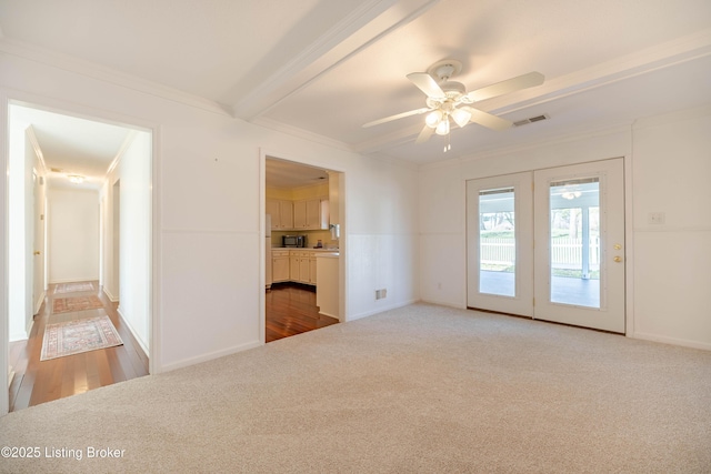 empty room featuring crown molding, carpet flooring, a ceiling fan, and visible vents