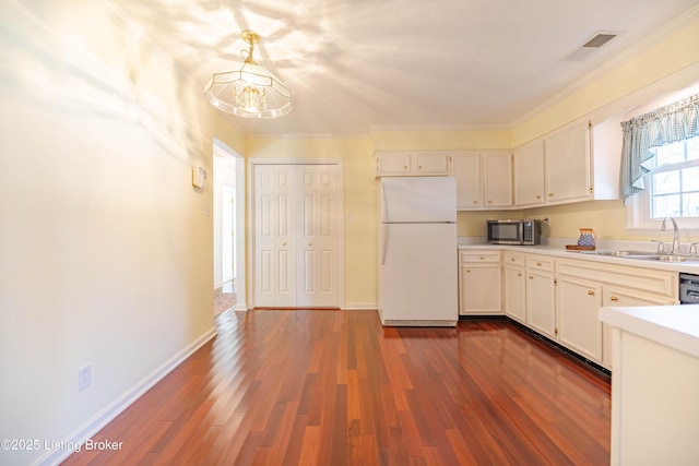 kitchen featuring freestanding refrigerator, dark wood-type flooring, visible vents, stainless steel microwave, and a sink