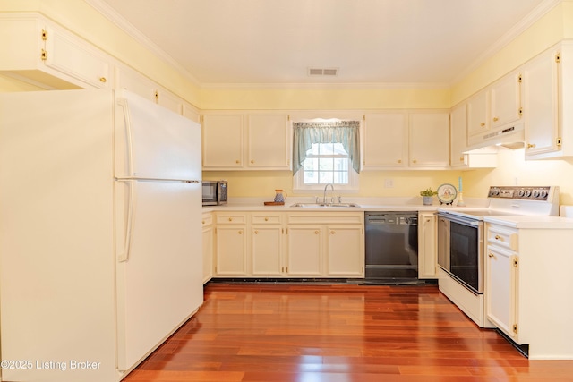 kitchen featuring visible vents, a sink, white appliances, dark wood finished floors, and under cabinet range hood