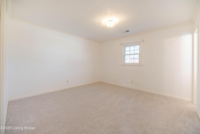 spare room with visible vents, baseboards, crown molding, and carpet floors