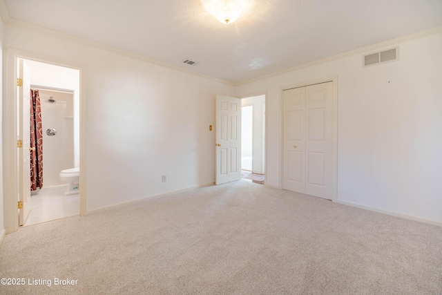 unfurnished bedroom with baseboards, a closet, ornamental molding, carpet floors, and visible vents