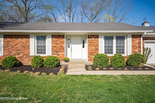view of front of home with a garage, a front yard, and brick siding