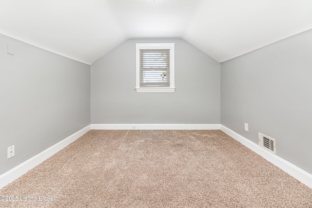 additional living space with visible vents, carpet floors, baseboards, and lofted ceiling