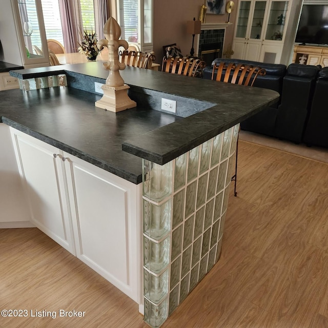 404 Eastgate Village Wynde, Louisville, KY 40223 - kitchen with a tiled fireplace, light wood finished floors, a breakfast bar, and dark countertops