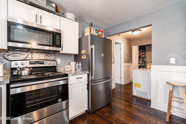 kitchen featuring appliances with stainless steel finishes, dark wood-style flooring, light stone counters, and white cabinetry