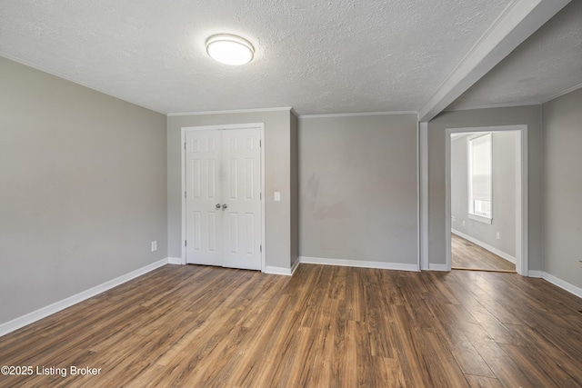 unfurnished bedroom featuring a closet, wood finished floors, a textured ceiling, and baseboards