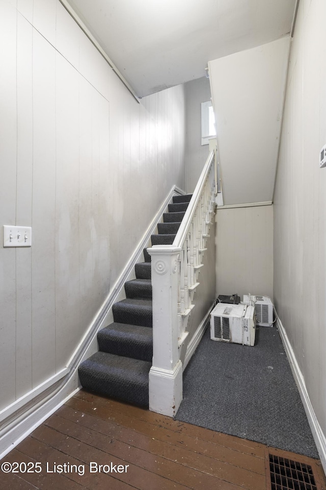 stairs featuring hardwood / wood-style flooring and wooden walls