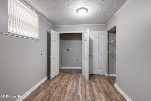 unfurnished bedroom with a textured ceiling, dark wood-style flooring, baseboards, a closet, and ornamental molding