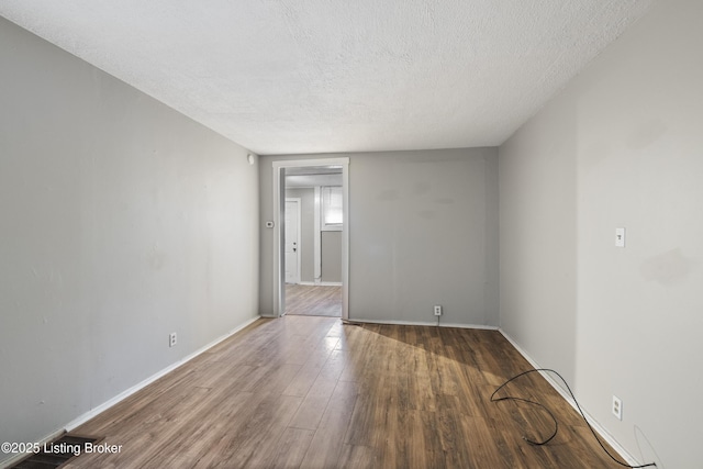 empty room with wood finished floors, a textured ceiling, and baseboards