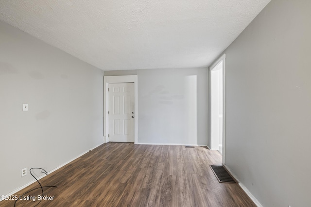 spare room with wood finished floors, visible vents, and baseboards