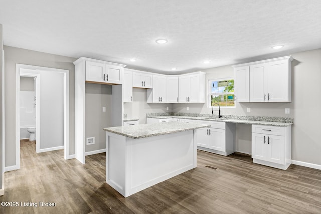 3408 Rhodelia Rd, Payneville, KY 40157 - kitchen featuring wood finished floors, white cabinets, a center island, recessed lighting, and light stone counters