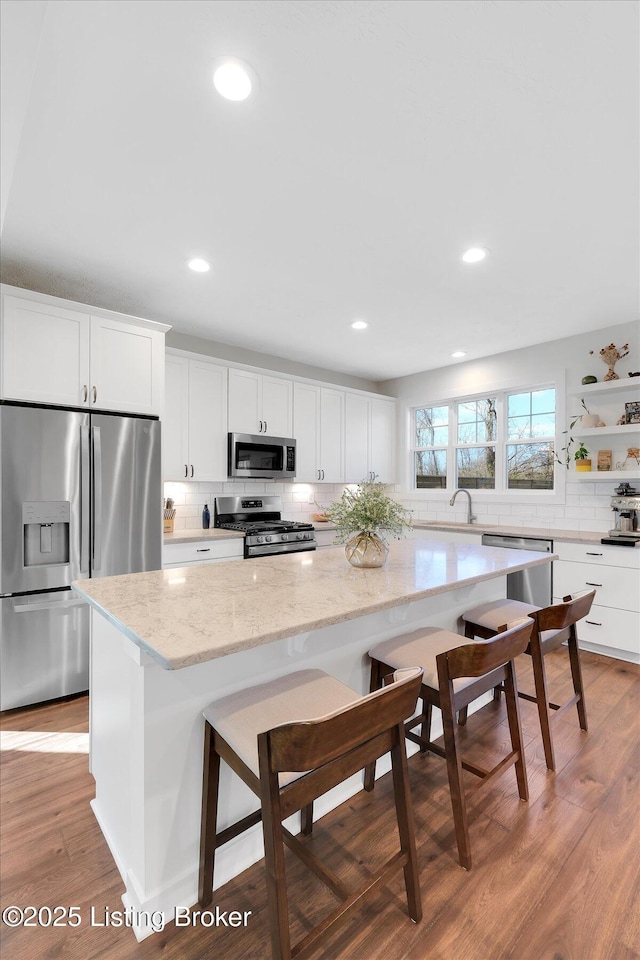 kitchen featuring decorative backsplash, light wood finished floors, white cabinetry, and stainless steel appliances