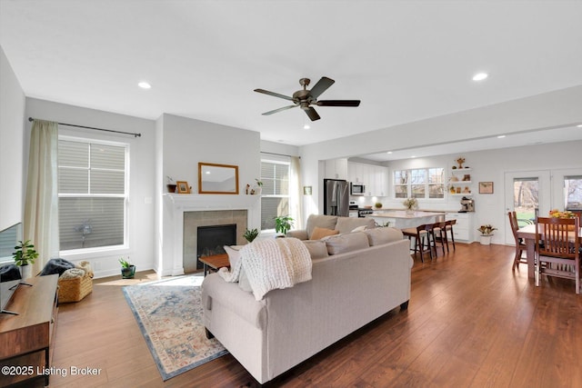 living area featuring ceiling fan, a fireplace, a wealth of natural light, dark wood-type flooring, and recessed lighting