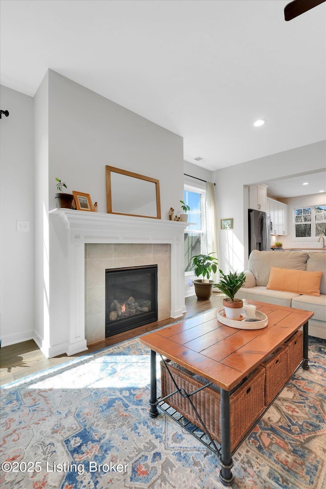 living area with a tiled fireplace, baseboards, recessed lighting, and wood finished floors