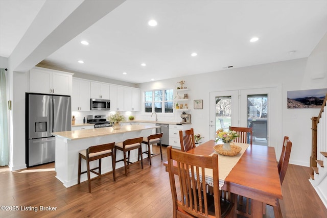 dining area featuring light wood finished floors, baseboards, stairway, and recessed lighting