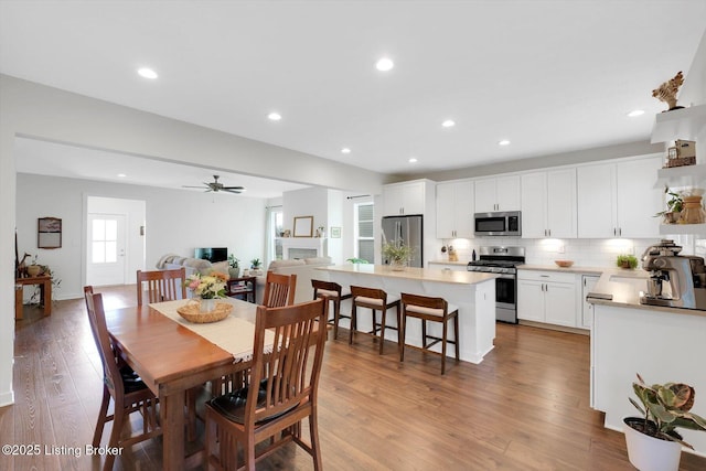 dining space with ceiling fan, light wood finished floors, and recessed lighting