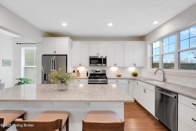 kitchen with tasteful backsplash, a sink, stainless steel appliances, a breakfast bar area, and plenty of natural light