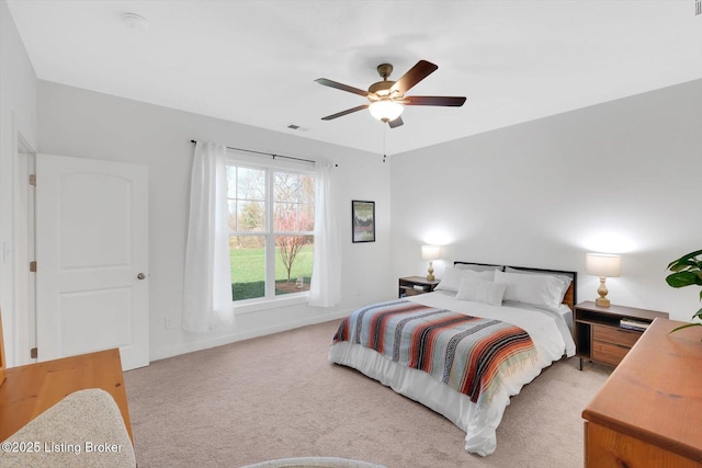 bedroom with visible vents, light colored carpet, baseboards, and a ceiling fan