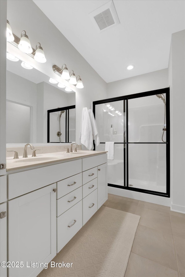 full bathroom with a stall shower, double vanity, a sink, and visible vents
