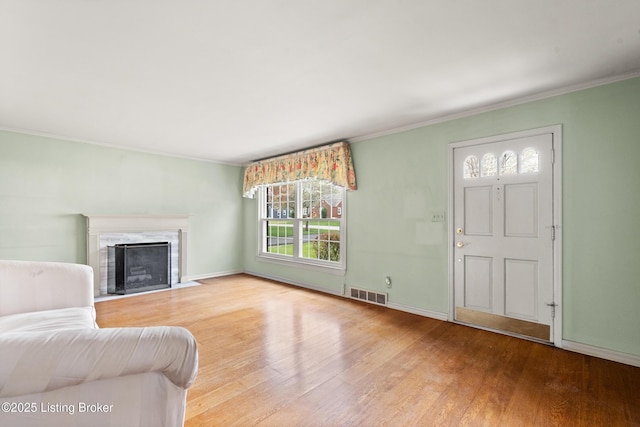 living area featuring crown molding, wood finished floors, visible vents, and a wealth of natural light