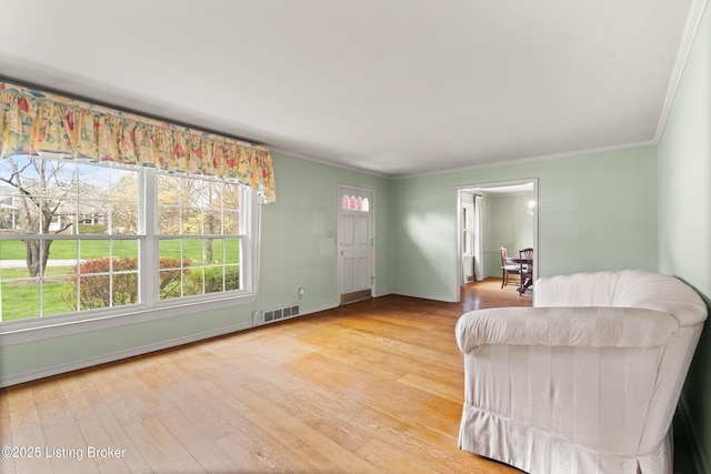 sitting room featuring visible vents, baseboards, crown molding, and wood finished floors
