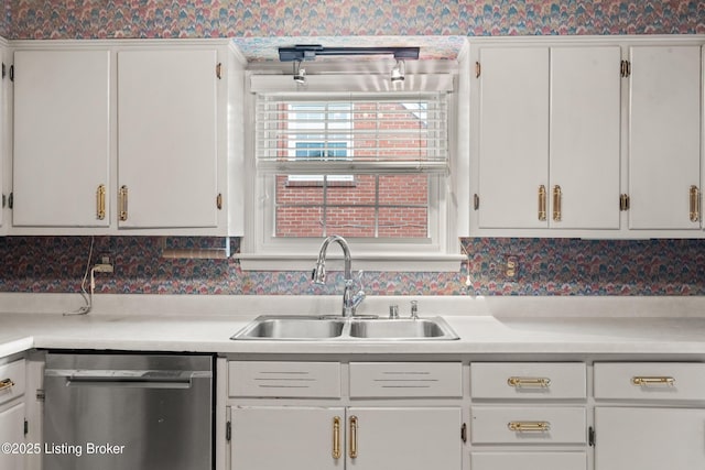 kitchen featuring wallpapered walls, stainless steel dishwasher, a sink, and white cabinetry