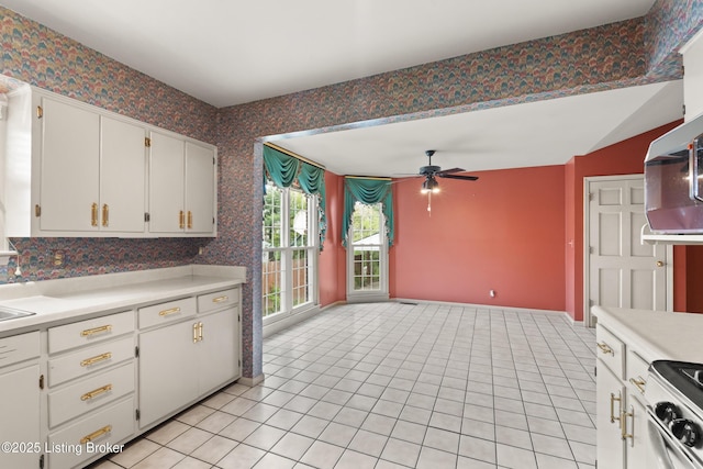 kitchen with wallpapered walls, light countertops, white cabinetry, white electric stove, and ceiling fan