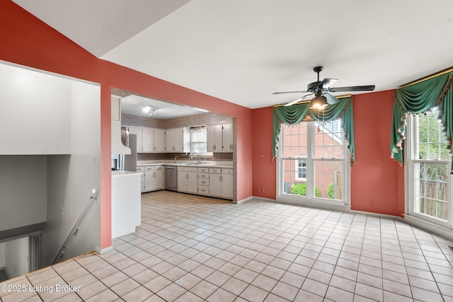 kitchen featuring stainless steel dishwasher, white cabinetry, a ceiling fan, light countertops, and baseboards