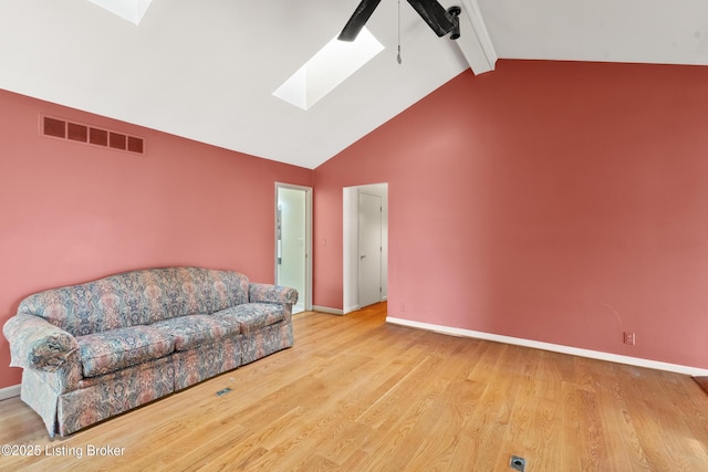 living area featuring baseboards, a ceiling fan, visible vents, lofted ceiling with skylight, and wood finished floors