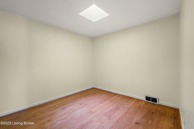 spare room featuring visible vents, baseboards, a skylight, and light wood-style flooring