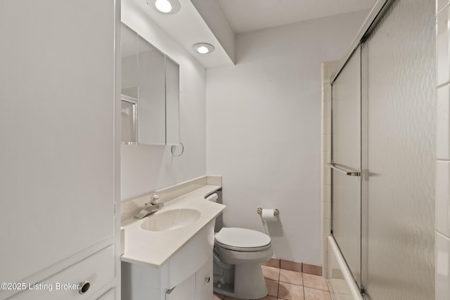 bathroom featuring tile patterned flooring, vanity, toilet, and bath / shower combo with glass door